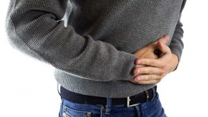 Man holding stomach due to abdominal pain from poor gut health.